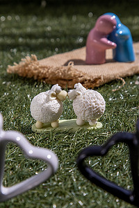 陶瓷情侣娃娃拥抱和绵羊陶瓷情侣娃娃亲吻在草坪上。