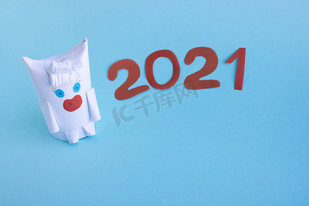 蓝色背景上用纸和卫生纸卷制成的有趣的白牛。新年的幻想。
