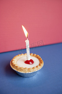 彩色背景下纸杯蛋糕上燃烧的蜡烛特写