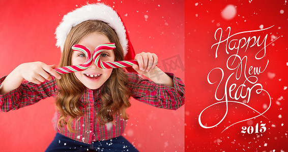 戴着圣诞帽拿着拐杖糖的快乐小女孩的合成图像