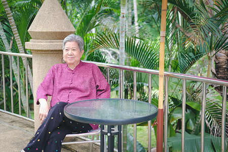 亚洲老年妇女在阳台露台上休息放松。
