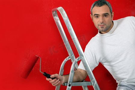 男人用滚筒刷画红墙