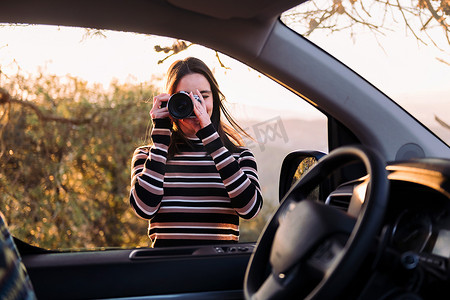 在公路旅行中用相机拍照的女人