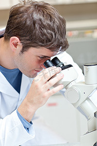 看通过显微镜的严肃的男性科学家