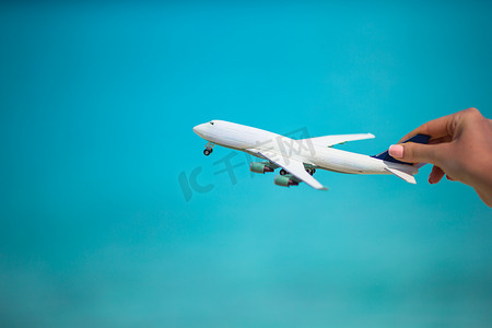 在绿松石海背景的小的白色玩具飞机
