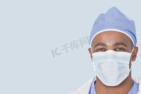 浅蓝色背景中戴面罩的男医生的特写