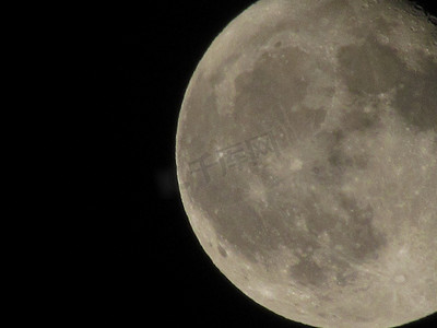 通过长焦相机拍摄的黑色夜空中的月亮特写。