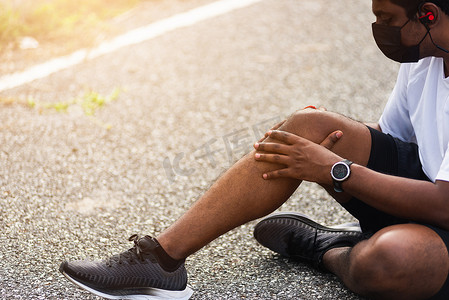跑步者黑人戴着手表坐着 他在跑步时用手关节支撑膝盖