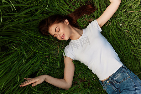 草地俯视图摄影照片_一个快乐的女人躺在草地上的俯视图