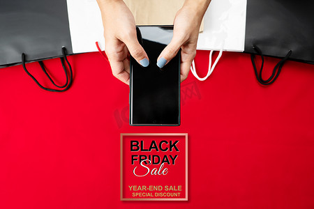 促销活动创意摄影照片_黑色星期五促销，女性在智能手机上进行网上购物
