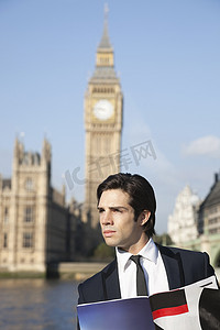 英国伦敦大本钟摄影照片_有思想的年轻商人拿着书反对英国伦敦大本钟钟楼