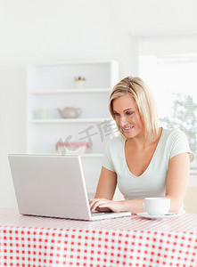 微笑的女人坐在桌旁，端着一杯咖啡和笔记本
