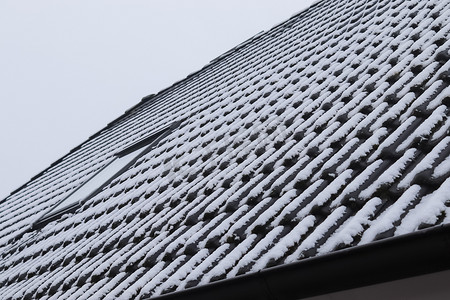 白雪房子摄影照片_欧洲房子冬天屋顶瓦片上的白雪