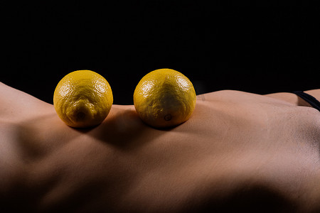 重量问题摄影照片_有橘皮组织问题的年轻女性和深色背景中的柠檬，特写