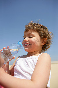 小孩在沙滩上喝瓶水