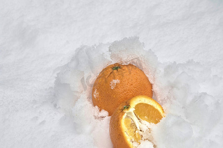 整个橙子和半橙子水果冷藏在花园的雪堆里