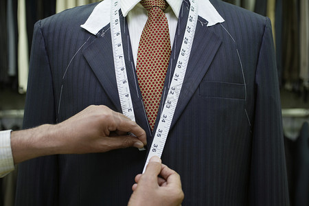 裁缝测量摄影照片_西装中间部分特写的裁缝测量商人