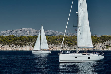 2019海摄影照片_克罗地亚，亚得里亚海，2019 年 9 月 15 日：背景是帆船比赛、帆船赛、水上帆的倒影、激烈的竞争、鲜艳的色彩、带风车的岛屿