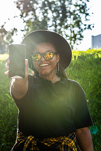 Z世代摄影照片_在城市-z 世代和城市概念中浏览社交网络的快乐非洲裔美国年轻女性的特写