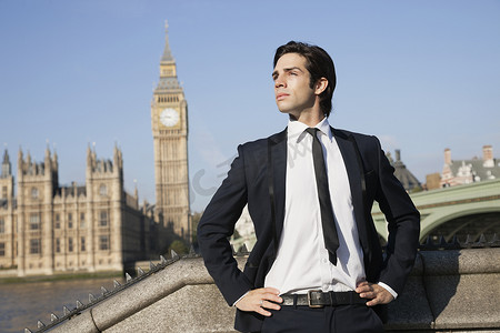 英国伦敦大本钟摄影照片_自信的年轻商人站在英国伦敦大本钟钟楼旁