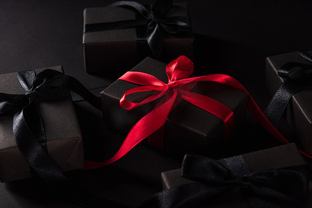绸带丝带飘带摄影照片_礼品盒包裹着黑纸和黑色蝴蝶结丝带