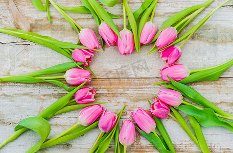 春天郁金香花摄影照片_质朴的木质背景上粉色郁金香花的浪漫之心