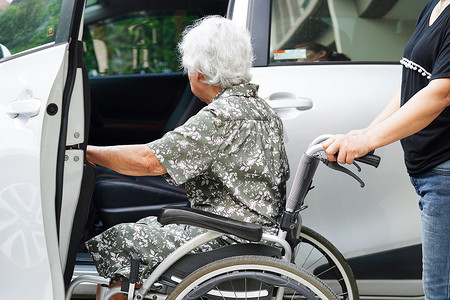 护理人员帮助亚洲老年妇女残疾患者上车，医疗理念。