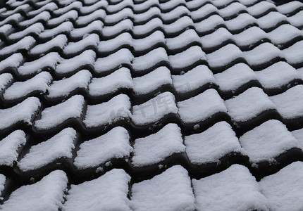 白雪房子摄影照片_欧洲房子冬天屋顶瓦片上的白雪