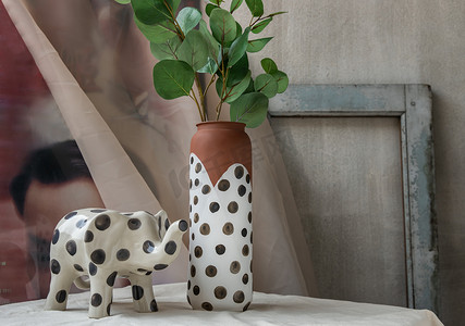 白色纹理桌布上的大象形陶瓷和手工陶瓷波尔卡圆点花瓶。
