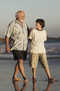 代沟摄影照片_黄昏时分，快乐的祖孙走在沙滩上