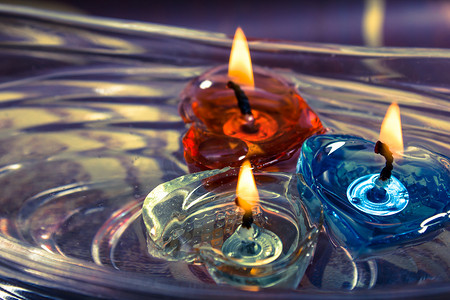 漂浮在水上的五颜六色的三支蜡烛芳香碗