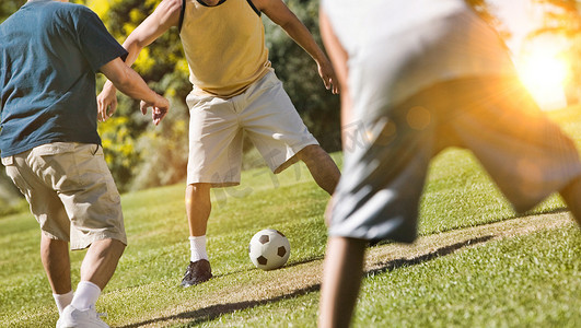 一群男子在锁定期间在公园里用镜头光晕踢足球