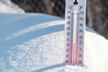 储存温度摄影照片_温度计位于雪地上，在蓝天的寒冷天气中显示负温度。空气和环境温度低的气象条件。气候变化和全球变暖