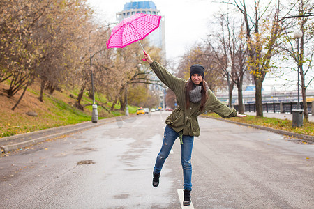 带伞的女孩摄影照片_秋雨天带伞走路的年轻女子