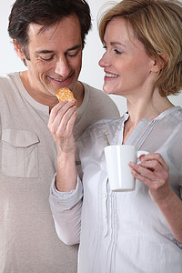 消化食物摄影照片_喝杯咖啡的女人给她的伴侣喂饼干