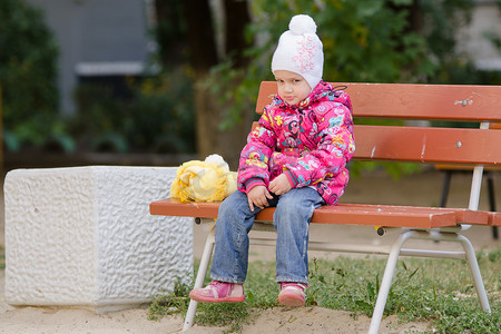 穿着秋装的阴沉女孩坐在长凳上