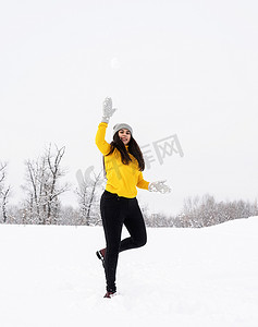 年轻的黑发女人在公园里玩雪