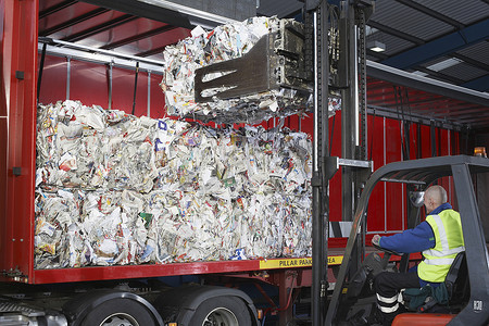 叉车工人将成堆的回收纸装载到卡车上
