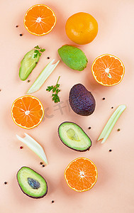 芹菜汁摄影照片_橙色背景下由橙子、芹菜和鳄梨制成的创意夏季图案。