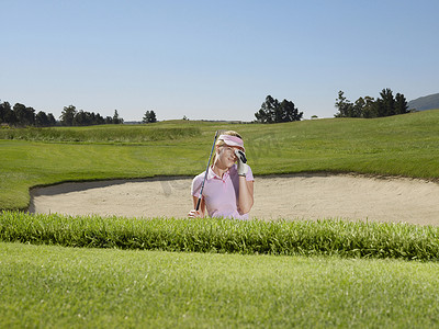 多人高尔夫摄影照片_沙坑的年轻失望的女性高尔夫球手