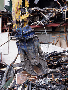 建筑物损坏摄影照片_拆除爪从被火灾损坏的失事建筑物中清除碎片和瓦砾