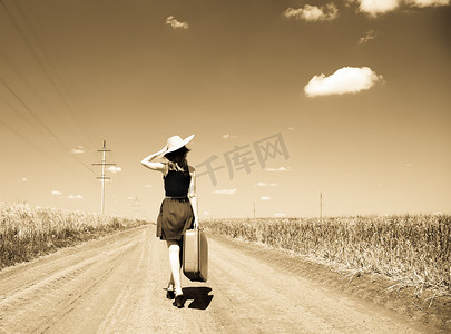 带着手提箱的孤独的女孩在乡下公路
