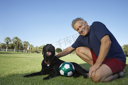 公园里一个带着狗和足球的快乐老人的画像