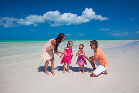 年轻漂亮的家庭，有两个女儿在海滩玩得开心