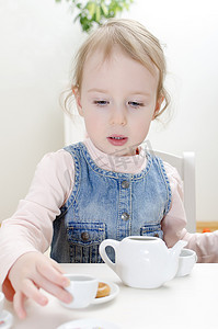 可爱的小杯子摄影照片_可爱的小女孩用百吉饼喝茶