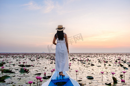 泰国乌隆他尼的红莲海 Kumphawapi 满是粉红色的花朵，亚洲女性在一艘船上。