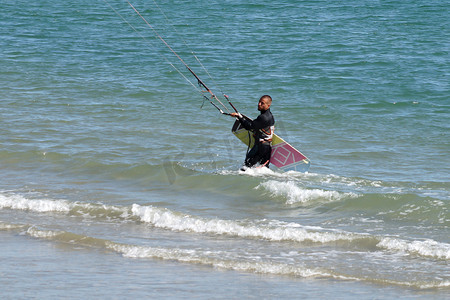 一个人拿着风筝冲浪板从海里出来