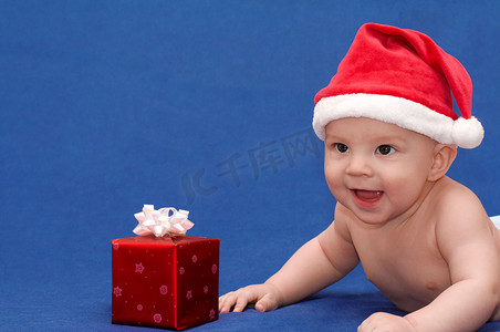 戴着圣诞帽、带着礼物微笑的婴儿