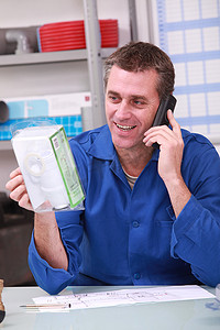 商家摄影照片_男子在水管工的商家中通过电话检查产品详细信息