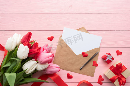 贺卡和信封，在粉红色的木质背景上，可以看到色彩缤纷的春郁金香